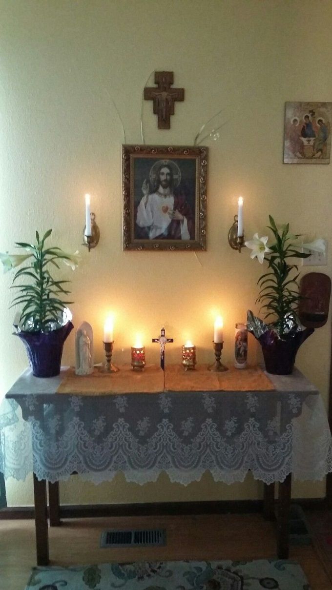 Altar laces with liturgical themes can be purchased by the yard from online church supply stores or other online sources. Fabric stores also have bridal sections that sell beautiful laces; or, as in this photo, you can simply find a beautiful lace table cloth. Again, notice the warm effect of candle glow. Many battery-run candles have built-in automatic timers that allow for running times of 5 hours or longer! Some also have remote controls so that you can place candles in higher places. These candles can be found in craft stores, such as Michaels, and home-decor stores.